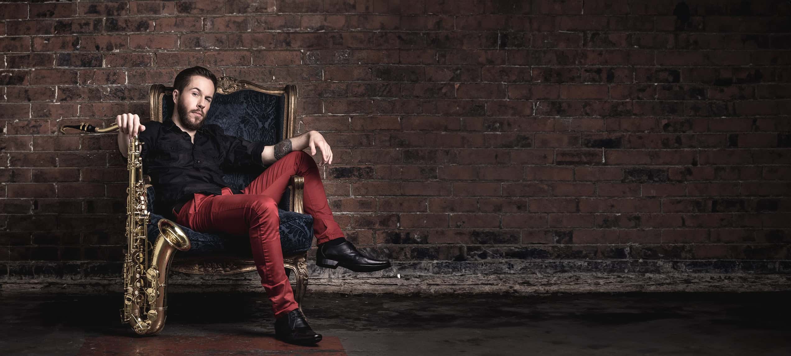 man sitting on chair with saxaphone